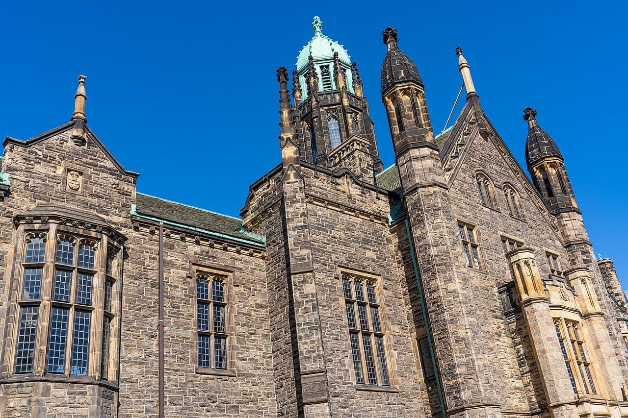 The stone towers of Trinity College, University of Toronto, against a blue sky